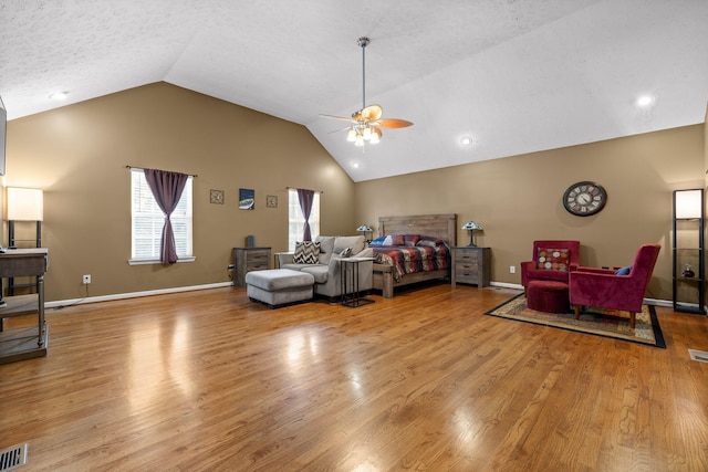 bedroom featuring ceiling fan, vaulted ceiling, a textured ceiling, and light hardwood / wood-style flooring