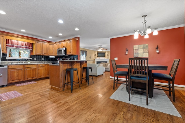 kitchen with a kitchen breakfast bar, light wood-type flooring, stainless steel appliances, pendant lighting, and a kitchen island