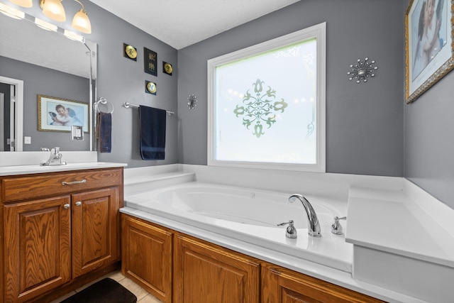 bathroom with a textured ceiling, plenty of natural light, a tub to relax in, and vanity