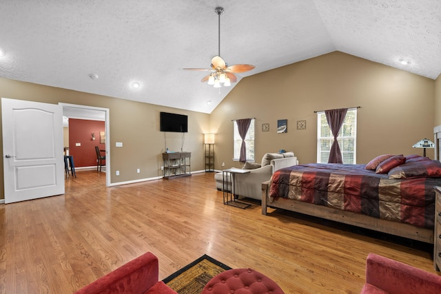 bedroom with a textured ceiling, ceiling fan, light hardwood / wood-style flooring, and lofted ceiling