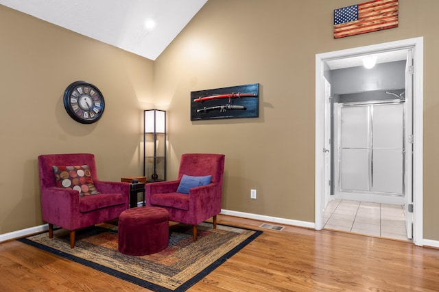 sitting room with hardwood / wood-style flooring and high vaulted ceiling