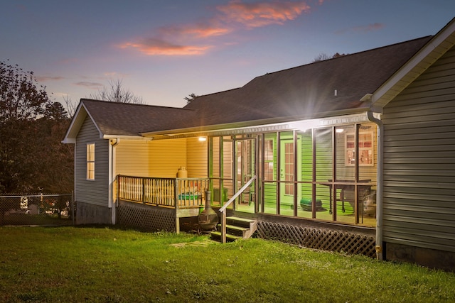 back house at dusk featuring a deck and a yard