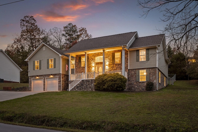 split foyer home featuring a yard, a porch, and a garage