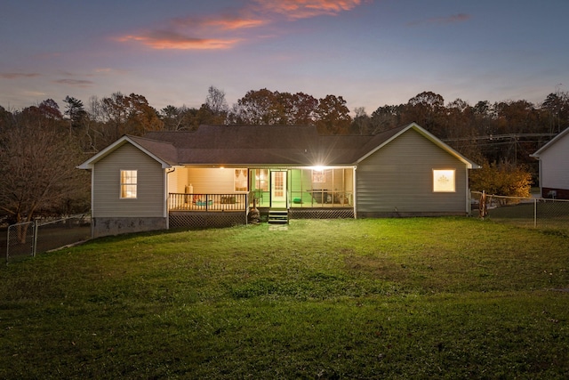 back house at dusk with a wooden deck and a yard