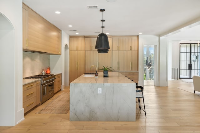 kitchen with sink, double oven range, hanging light fixtures, and light hardwood / wood-style flooring