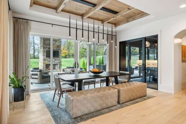 dining room with beam ceiling, light hardwood / wood-style flooring, and wood ceiling