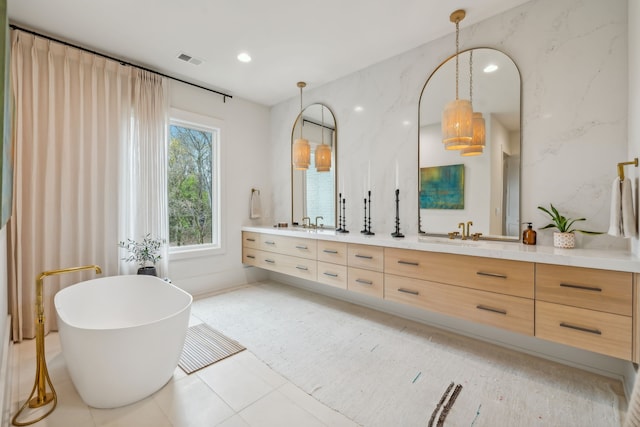 bathroom featuring tile patterned flooring, vanity, and a bath