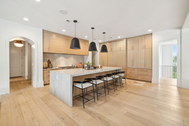 kitchen featuring light brown cabinets, light wood-type flooring, and a kitchen island with sink