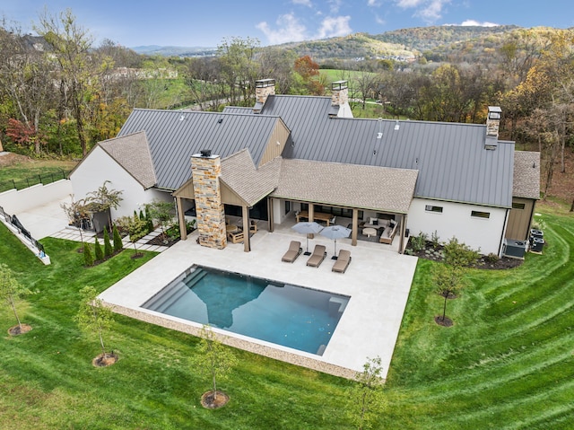 back of property featuring an outdoor living space with a fireplace, a patio area, and a lawn