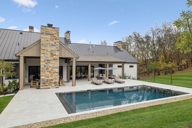 back of property featuring an outdoor living space with a fireplace, a yard, and a patio