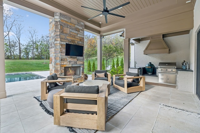 view of patio with an outdoor stone fireplace, ceiling fan, grilling area, and exterior kitchen