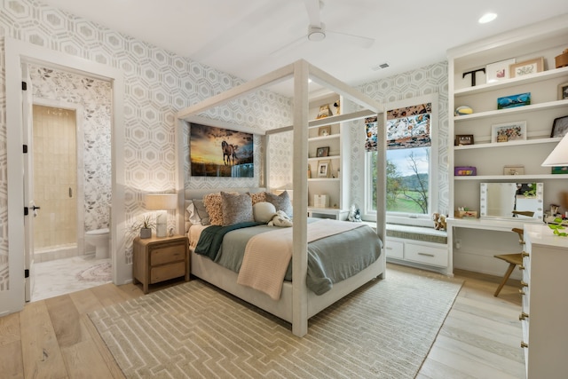 bedroom featuring hardwood / wood-style flooring, ceiling fan, built in desk, and connected bathroom