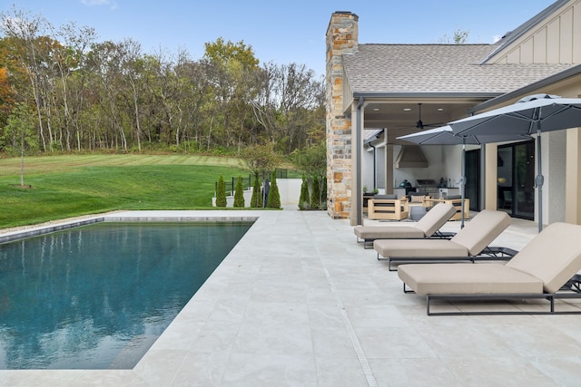 view of swimming pool featuring a yard, an outdoor kitchen, a patio, and ceiling fan