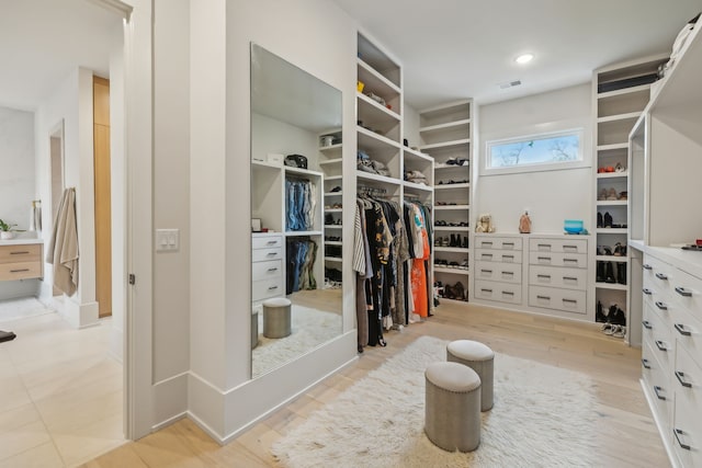 walk in closet with light hardwood / wood-style flooring