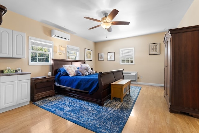 bedroom with light hardwood / wood-style floors, a wall unit AC, and ceiling fan