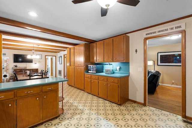 kitchen with hanging light fixtures, ceiling fan, light wood-type flooring, ornamental molding, and beamed ceiling