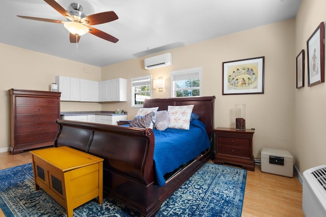 bedroom with ceiling fan, light wood-type flooring, and an AC wall unit