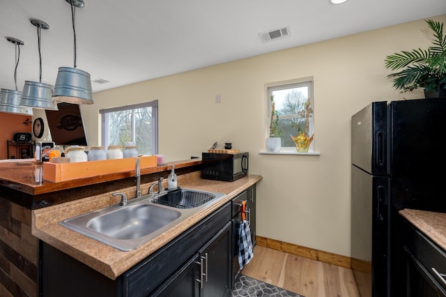 kitchen with light hardwood / wood-style flooring, a kitchen island, black appliances, and sink