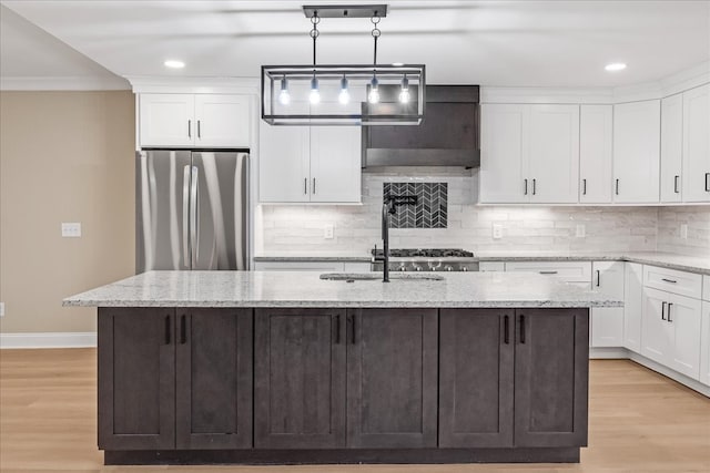 kitchen featuring stainless steel refrigerator, a kitchen island with sink, light hardwood / wood-style flooring, and pendant lighting