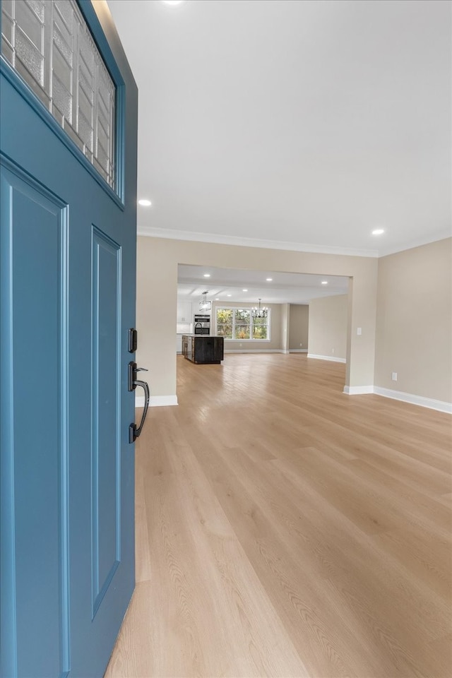 foyer with crown molding and light hardwood / wood-style flooring