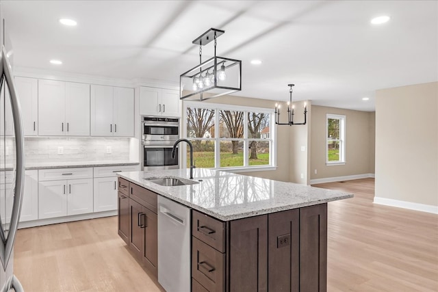 kitchen with white cabinets, decorative light fixtures, sink, and appliances with stainless steel finishes