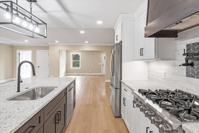 kitchen with white cabinetry, light stone countertops, sink, exhaust hood, and appliances with stainless steel finishes