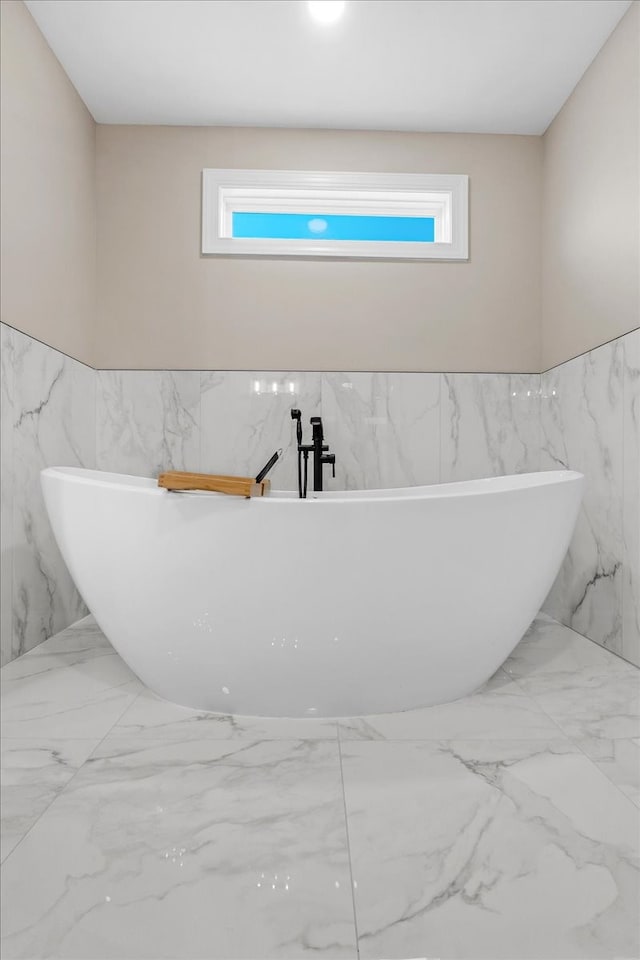 bathroom with a wealth of natural light, a washtub, and tile walls