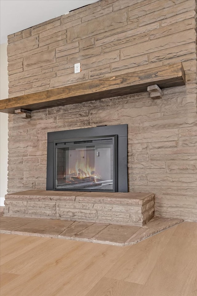 interior details featuring a stone fireplace and wood-type flooring