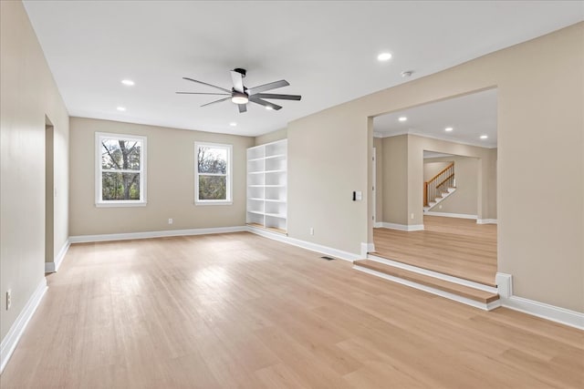 spare room with light wood-type flooring, built in features, and ceiling fan