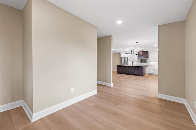 hallway featuring light hardwood / wood-style flooring, a notable chandelier, and sink