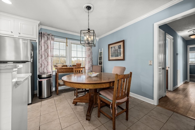 dining area featuring light tile patterned floors, crown molding, and an inviting chandelier