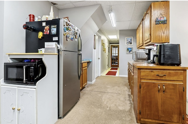 kitchen featuring brown cabinetry, black microwave, and a drop ceiling