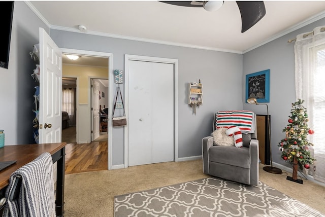 living area featuring ornamental molding, carpet flooring, baseboards, and a ceiling fan