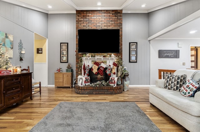 living room featuring recessed lighting, a brick fireplace, wood finished floors, and crown molding