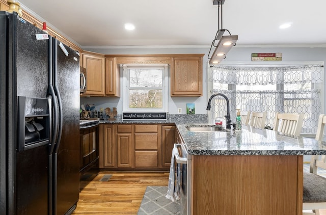 kitchen featuring crown molding, light wood finished floors, a sink, a peninsula, and black appliances