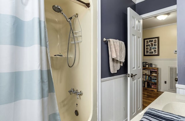 full bath featuring shower / bath combo, visible vents, a wainscoted wall, ornamental molding, and wood finished floors