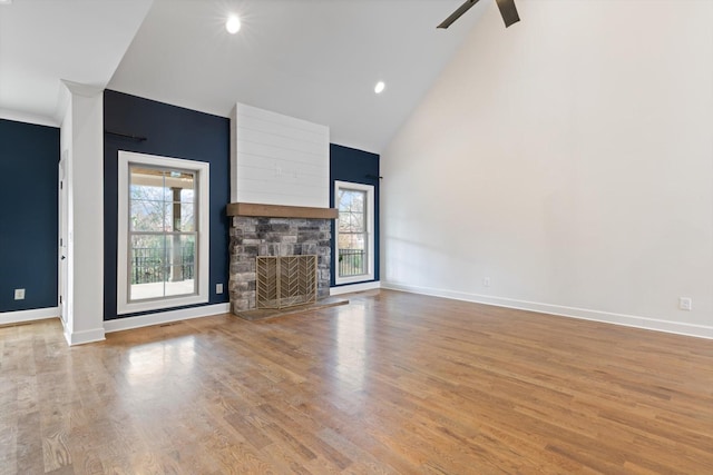 unfurnished living room with ceiling fan, a fireplace, high vaulted ceiling, and light hardwood / wood-style floors