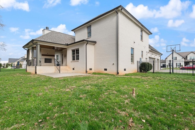 back of property with a lawn, a garage, and a patio area