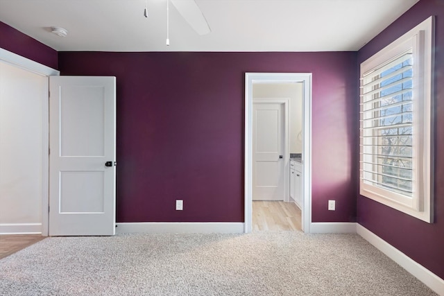 unfurnished bedroom featuring ensuite bathroom, ceiling fan, and light colored carpet