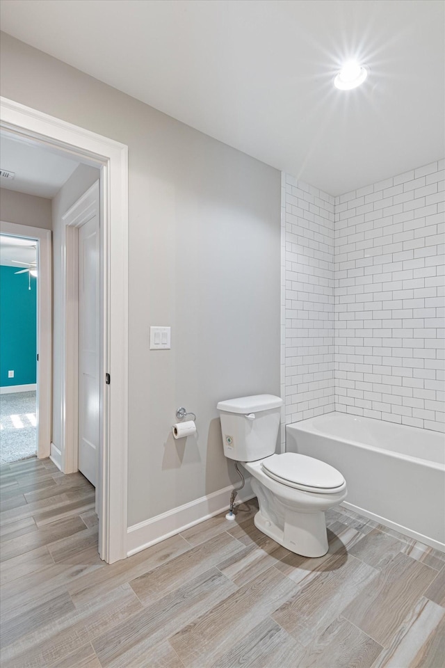 bathroom featuring tiled shower / bath, wood-type flooring, and toilet