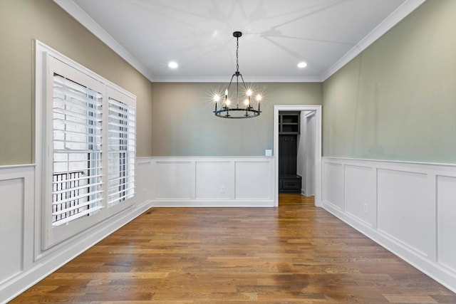 unfurnished dining area with dark hardwood / wood-style floors, crown molding, and an inviting chandelier