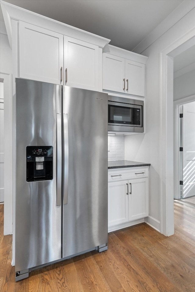 kitchen featuring white cabinetry, stainless steel appliances, tasteful backsplash, hardwood / wood-style floors, and ornamental molding