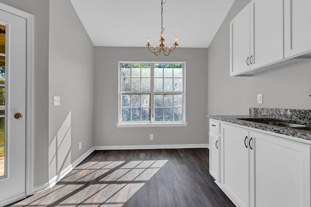 kitchen featuring white cabinetry, sink, an inviting chandelier, dark hardwood / wood-style floors, and dark stone counters