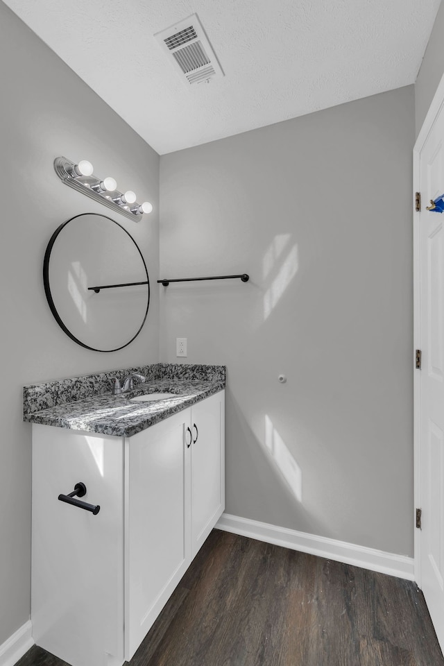 bathroom featuring vanity, wood-type flooring, and a textured ceiling