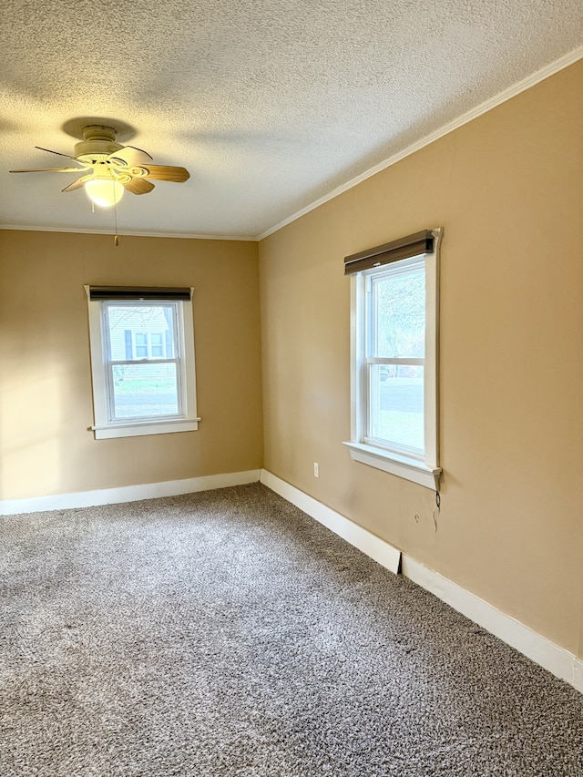 carpeted spare room with ornamental molding, a textured ceiling, ceiling fan, and a healthy amount of sunlight