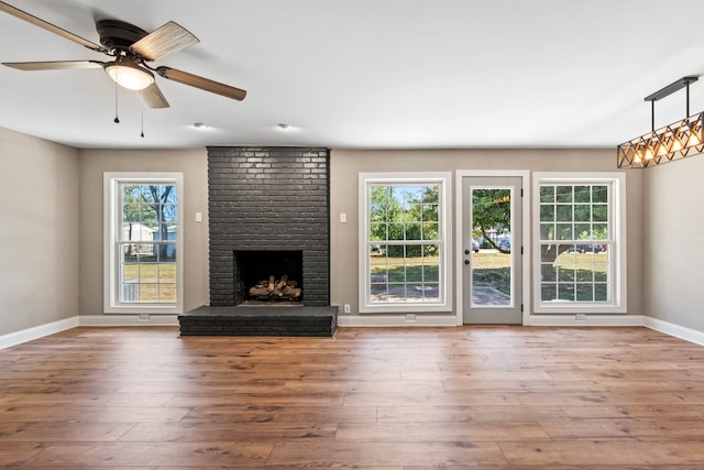 unfurnished living room with a brick fireplace, ceiling fan, and hardwood / wood-style flooring