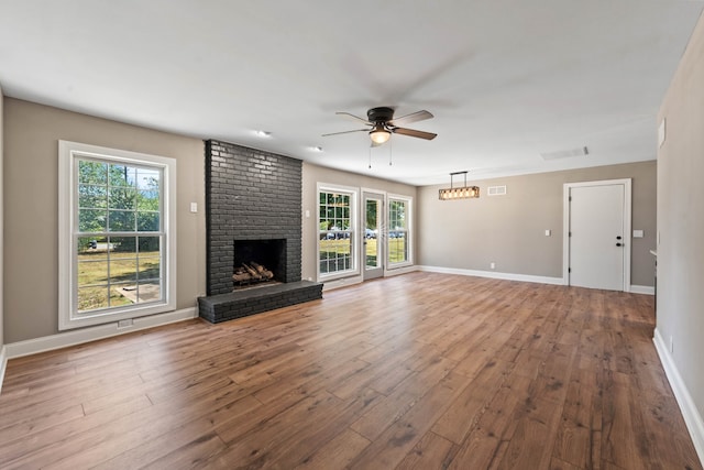 unfurnished living room featuring wood-type flooring, a brick fireplace, and ceiling fan