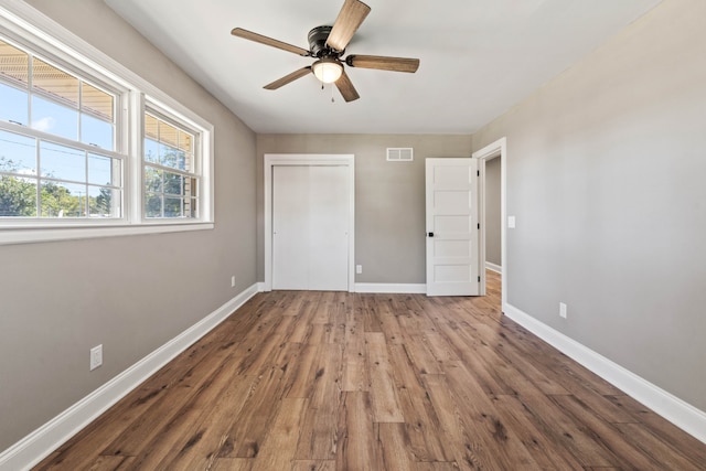 unfurnished bedroom featuring wood-type flooring, a closet, and ceiling fan