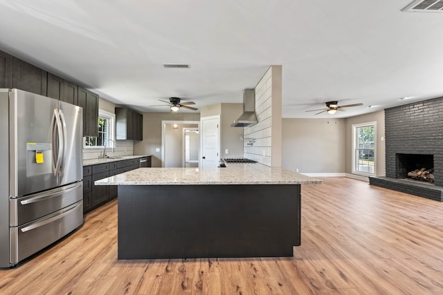 kitchen with a fireplace, stainless steel fridge, a center island, and light hardwood / wood-style floors