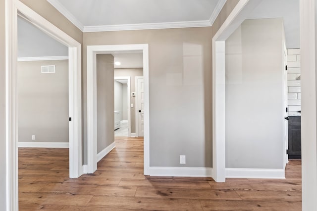 hallway with light hardwood / wood-style floors and crown molding